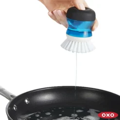OXO täytettävä pannutiskiharja lepoalustalla
